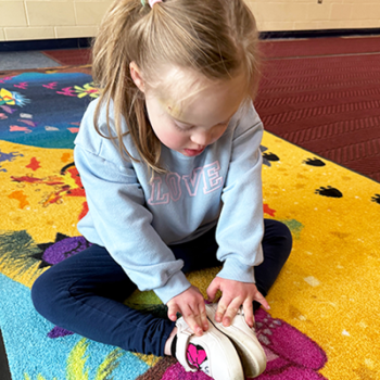 Down Syndrome child imitating a yoga dinosaur
